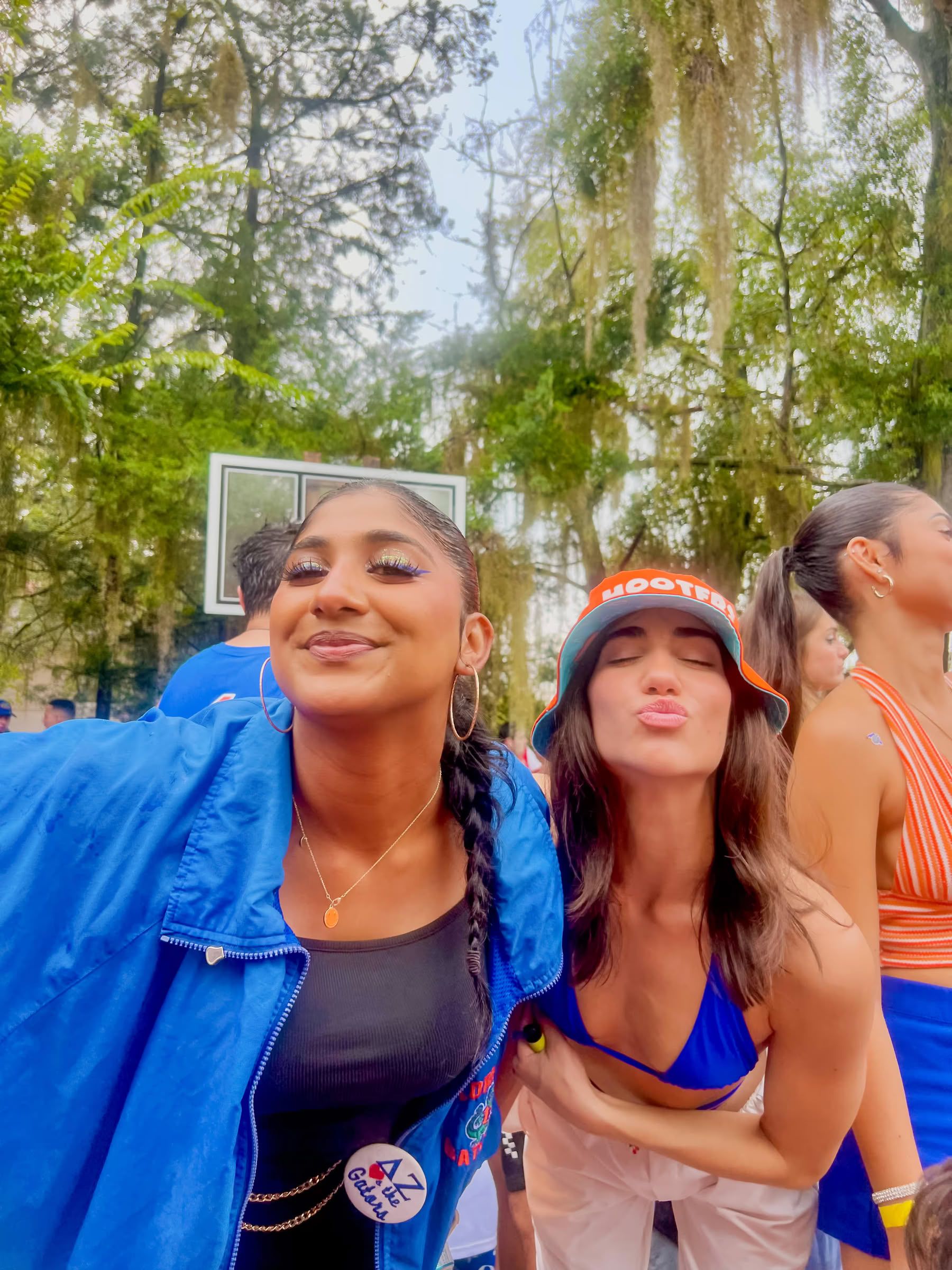 Ufora Student Living Apartments Two women posing and smiling outdoors, one wearing a blue jacket, the other in a hat and blue top, with trees behind them.